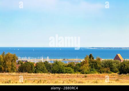 Heiligenhafen/Ostsee, Deutschland - 25. Juli 2019: Ostsee mit weißen Segelbooten und Hafen von Heiligenhafen bei schönem Sommerwetter. Heiligenha Stockfoto