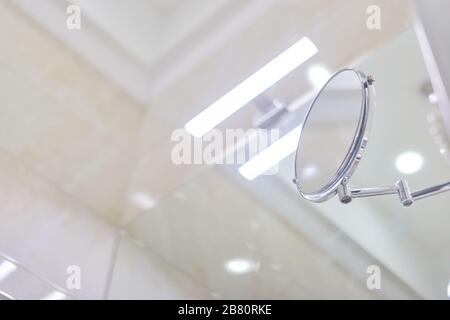 Badezimmer innen, Nahaufnahme Detail. Teil der Zierdecke, LED-Licht über dem Waschbeckenspiegel, Kosmetikspiegel, beige Marmorfliesen auf der TH Stockfoto