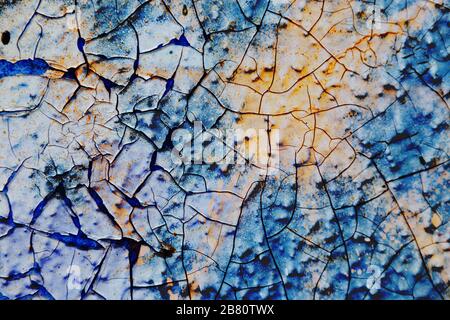Oberflächentextur mit blauer und gelber Farbe auf einer Oberflächenstruktur mit dickem Lack und mit Rissen. Für abstrakte Hintergründe. Deutschland Stockfoto