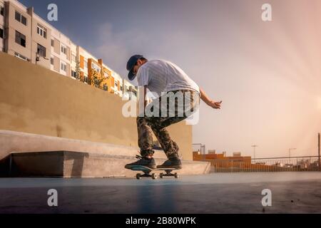 Foto 4 (Landung). Der junge Skater macht einen Trick, der als boneless bezeichnet wird. Skateboarden Stockfoto