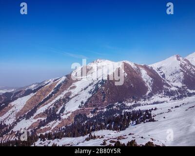 Blick auf die Winterberge und den blauen Himmel. Querformat. Winter Natur. Flug über Skibasis. Terskey Alatoo Mountains, Tian-Shan, Karakol, Kirgisistan. Stockfoto