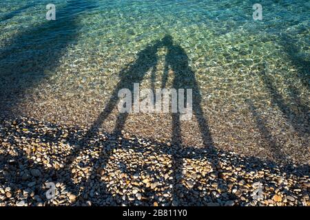 Ein liebevolles Paar an einem Strand, das Schatten im Meer erzeugt Stockfoto