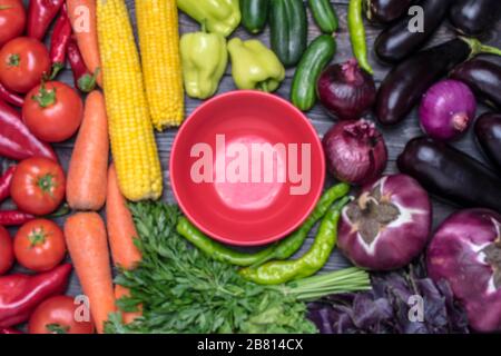 Tischanordnung mit verschiedenen frischen Früchten und Gemüse, sortiert nach Farben - Pfeffer, Tomate, Mais, Karotten, grünem Salat, Cilantro, Auberginen. Stockfoto