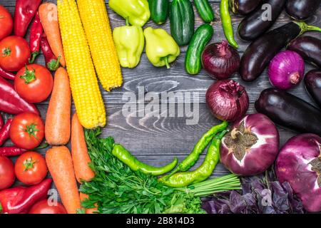 Tischanordnung mit verschiedenen frischen Früchten und Gemüse, sortiert nach Farben - Pfeffer, Tomate, Mais, Karotten, grünem Salat, Cilantro, Auberginen Stockfoto