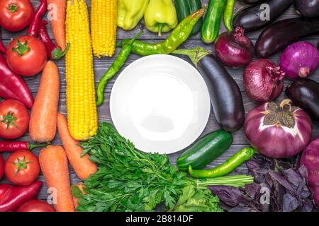 Tischanordnung mit verschiedenen frischen Früchten und Gemüse, sortiert nach Farben - Pfeffer, Tomate, Mais, Karotten, grünem Salat, Cilantro, Auberginen. Stockfoto