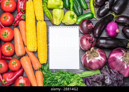 Tischanordnung mit verschiedenen frischen Früchten und Gemüse, sortiert nach Farben - Pfeffer, Tomate, Mais, Karotten, grünem Salat, Cilantro, Auberginen. Stockfoto