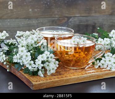Kräuterdorntee aus Blumenknospen rund um blühende Äste auf Holzschneidebrett auf rustikalem Hintergrund, Nahaufnahme, Kopierraum, Herzgesundheit und Erbsen Stockfoto