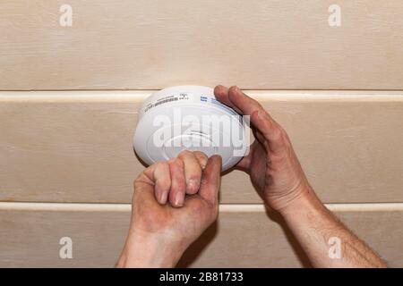 Rauchmelder an einer Decke, Installation eines Rauchmelders an einer Decke in Berlin Stockfoto