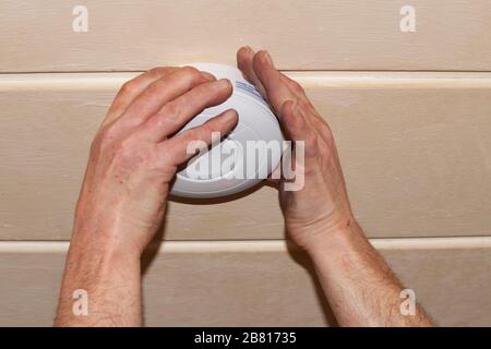 Rauchmelder an einer Decke, Installation eines Rauchmelders an einer Decke in Berlin Stockfoto