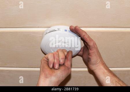 Rauchmelder an einer Decke, Installation eines Rauchmelders an einer Decke in Berlin Stockfoto
