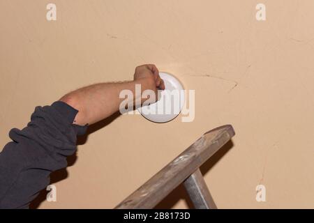 Rauchmelder an einer Decke, Installation eines Rauchmelders an einer Decke in Berlin Stockfoto