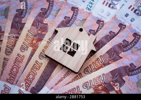Hypotheken-, Versicherungs-, Kauf- und Mietgeschäft, Immobiliengeschäft. Kleines Holzhausspielzeug auf Geldrubel Banknoten Hintergrund Seitenansicht Stockfoto