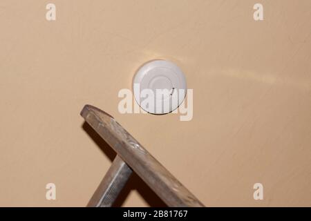 Rauchmelder an einer Decke, Installation eines Rauchmelders an einer Decke in Berlin Stockfoto