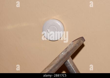 Rauchmelder an einer Decke, Installation eines Rauchmelders an einer Decke in Berlin Stockfoto