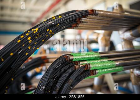 Drahtbündel hängt bei der Herstellung von Elektronikteilen für große Werksstrukturen von Leitungen. Konzept Fertigung von Industrieteilen Stockfoto