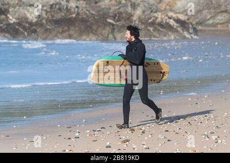 Ein eifriger Stocher-Surfer, der an der Küste von Fistral in Newquay in Cornwall entlang läuft. Stockfoto