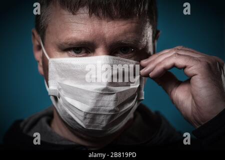 Ein Mann passt eine medizinische Maske auf sein Gesicht an. Pandemie COVID-19 Stockfoto