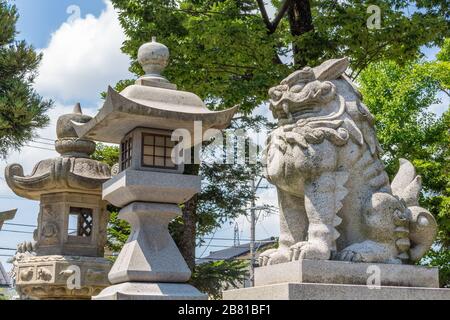 Löwenhund, oder komainu, mit Steinlaternen, am Miumajinja shinto Schrein, Kanazawa, Japan. Diese traditionellen Statuen sind paarweise in den meisten Schreinen a zu sehen Stockfoto