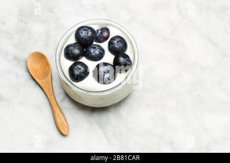 Blaubeeren mit Sahne in einem Kristallglas auf einem Marmortisch Stockfoto