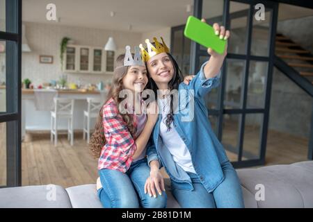 Mutter und Tochter tragen Kronen und machen Fotos Stockfoto