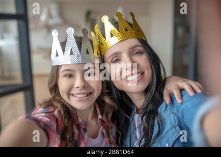 Mutter und Tochter tragen Kronen und lächeln Stockfoto
