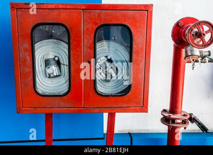 Wandaufhängender Feuerlöscher, Brandsicherheit und Notfallausrüstung in der Wandmontage des Red Blue Box Architekturfeuerlöschers Glasschrank i Stockfoto