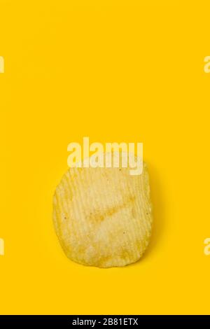 Ein einsamer Kartoffelchip auf gelbem Hintergrund Stockfoto