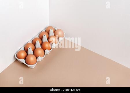 Ein Dutzend Eier in einer Schachtel auf dem Tisch, Vorderansicht. Minimalistisches Produktkonzept. Stockfoto