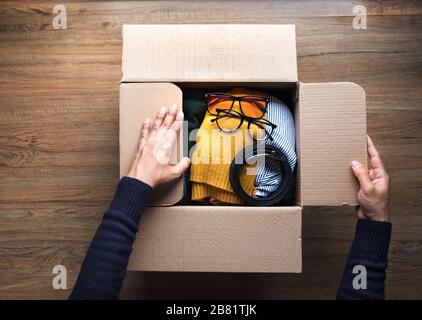 Spenden Konzepte mit jungen Menschen Verpackung Accessoires Kleidung in brauner Box.geben und mit human.second teilen Hand oder recyceln Produktideen Stockfoto