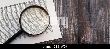 Lupe auf dem Finanzbericht, auf Holztisch legen. Finanzierungs-Trading-Konzept Stockfoto