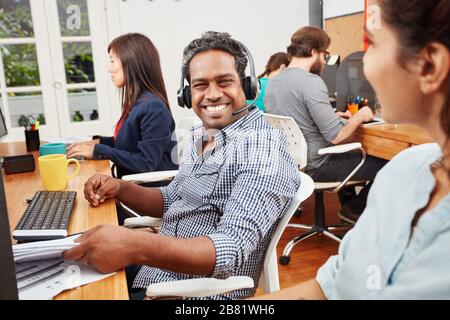 Lächelnder Mann in Indien arbeitet im Callcenter als Kundenservice Stockfoto