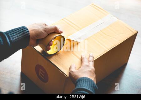 Schließen Sie die Verpackungsbox für die Handverpackung von Männern von Tape.Business Online Shopping.logistischer Transport Service.Moving Home Concepts Stockfoto