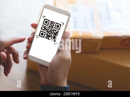 Online-Shopping-Konzepte mit youngman mit Smartphone mit qr-Code auf Produktpaket Box.E Commerce Market.Transportation Logistic.Business Retail. Stockfoto