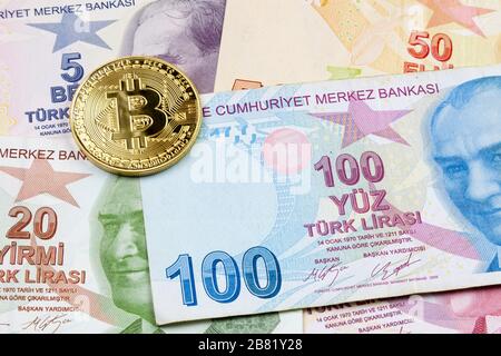 Nahaufnahme einer goldenen Bitcoin-Münze auf einem Stapel türkischer Lira-Banknoten. Stockfoto