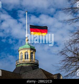 Blick auf die deutsche Fahne am Halbmast, auf Halbmast, auf dem Turmdach von Schloss Karlsruhe, blauer Himmel dahinter. Deutschland. Stockfoto