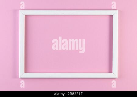 Weißer Holzrahmen auf pinkfarbenem Pastell-Hintergrund. Minimales kreatives Konzept. Stockfoto