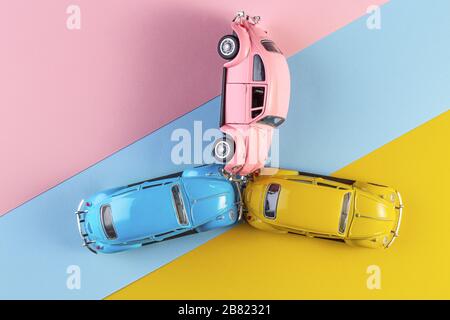 Spielzeugautos im Unfall auf einem pastellfarbenen Hintergrund. Drei Unfallherden, Autoabsturzversicherung. Rennwagen auf der Rennstrecke. Stockfoto