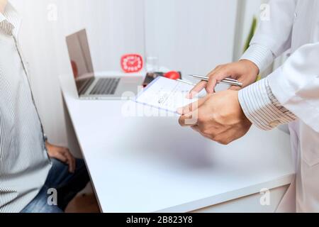 Ein Arzt berät Patienten, während am Tisch im Büro zu sitzen. Medizin und Gesundheit Konzept. Stockfoto