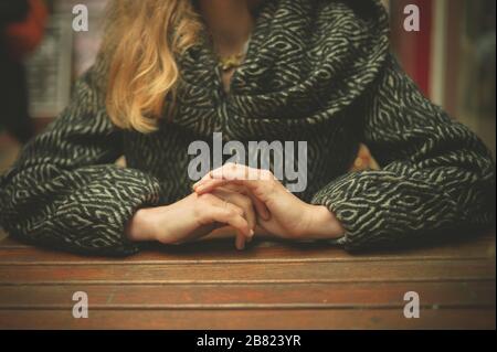 Eine junge Frau sitzt im Winter an einem Tisch im Freien Stockfoto