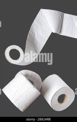 Rollen weißes toilettenpapier liegen auf schwarzem Hintergrund Stockfoto