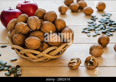 Walnüsse in einem Korb, Äpfel und Kürbissamen auf Baumhintergrund Stockfoto