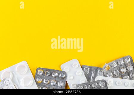 Ein Stapel verwendete Blisterpackungen mit Pillen auf gelbem Hintergrund. Medizinische Blisterpackungen geöffnet und leer ohne Pillen Draufsicht. Medizinische und medizinische Behandlung Stockfoto
