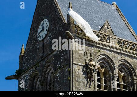 Der Amerikaner John Steele Fallschirmjäger Denkmal an der Kirche auf dem Dach ot Sainte-Mère l'Eglise, Normandie, Frankreich. Stockfoto