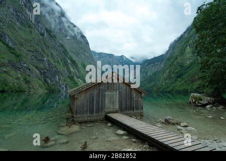 Holzhütte/Bootshaus am Obersee, umgeben von Bergen in Schönau am Koenigssee in den bayerischen Alpen, Nationalpark Berchtesgaden, Deutschland Stockfoto