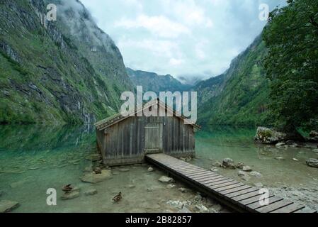 Holzhütte/Bootshaus am Obersee, umgeben von Bergen in Schönau am Koenigssee in den bayerischen Alpen, Nationalpark Berchtesgaden, Deutschland Stockfoto