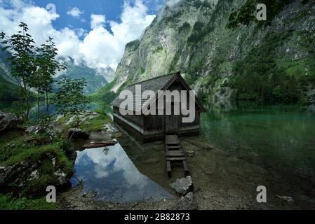 Holzhütte/Bootshaus am Obersee, umgeben von Bergen in Schönau am Koenigssee in den bayerischen Alpen, Nationalpark Berchtesgaden, Deutschland Stockfoto