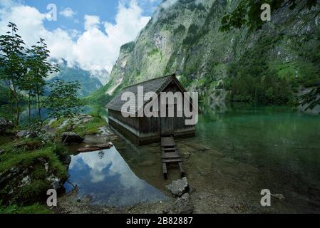 Holzhütte/Bootshaus am Obersee, umgeben von Bergen in Schönau am Koenigssee in den bayerischen Alpen, Nationalpark Berchtesgaden, Deutschland Stockfoto