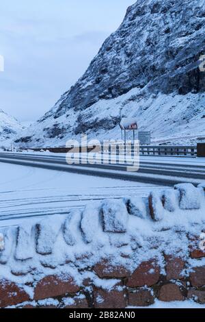 Fahren Sie auf der linken Seite in verschiedenen Sprachen und Sehenswürdigkeiten auf der Straße in schneebedeckten Glencoe, Highlands, Schottland im Winter Stockfoto