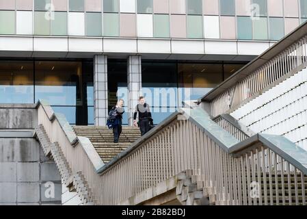 Brüssel Business District/ Belgien - 02 04 2020: Zwei Polizisten gehen die Treppe des Bundespolizeihauptquartiers hinunter Stockfoto