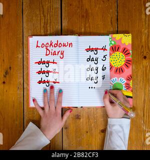 Mädchen, die in einem Tagebuch die Tage des Lockdowns herunterzählen Stockfoto